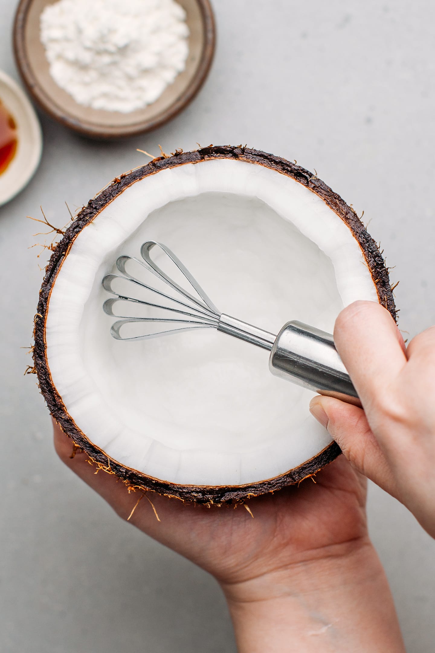 Grating a coconut using a coconut grater.