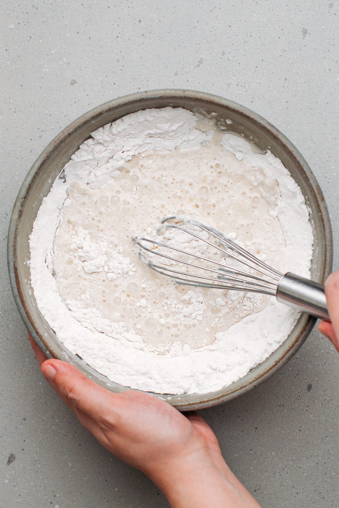 Whisking coconut milk with rice flour and sugar in a mixing bowl.