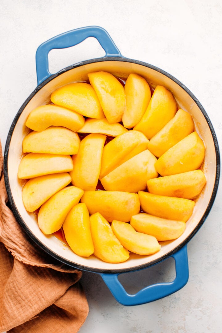 Apple slices arrange in a baking dish, on top of caramel.