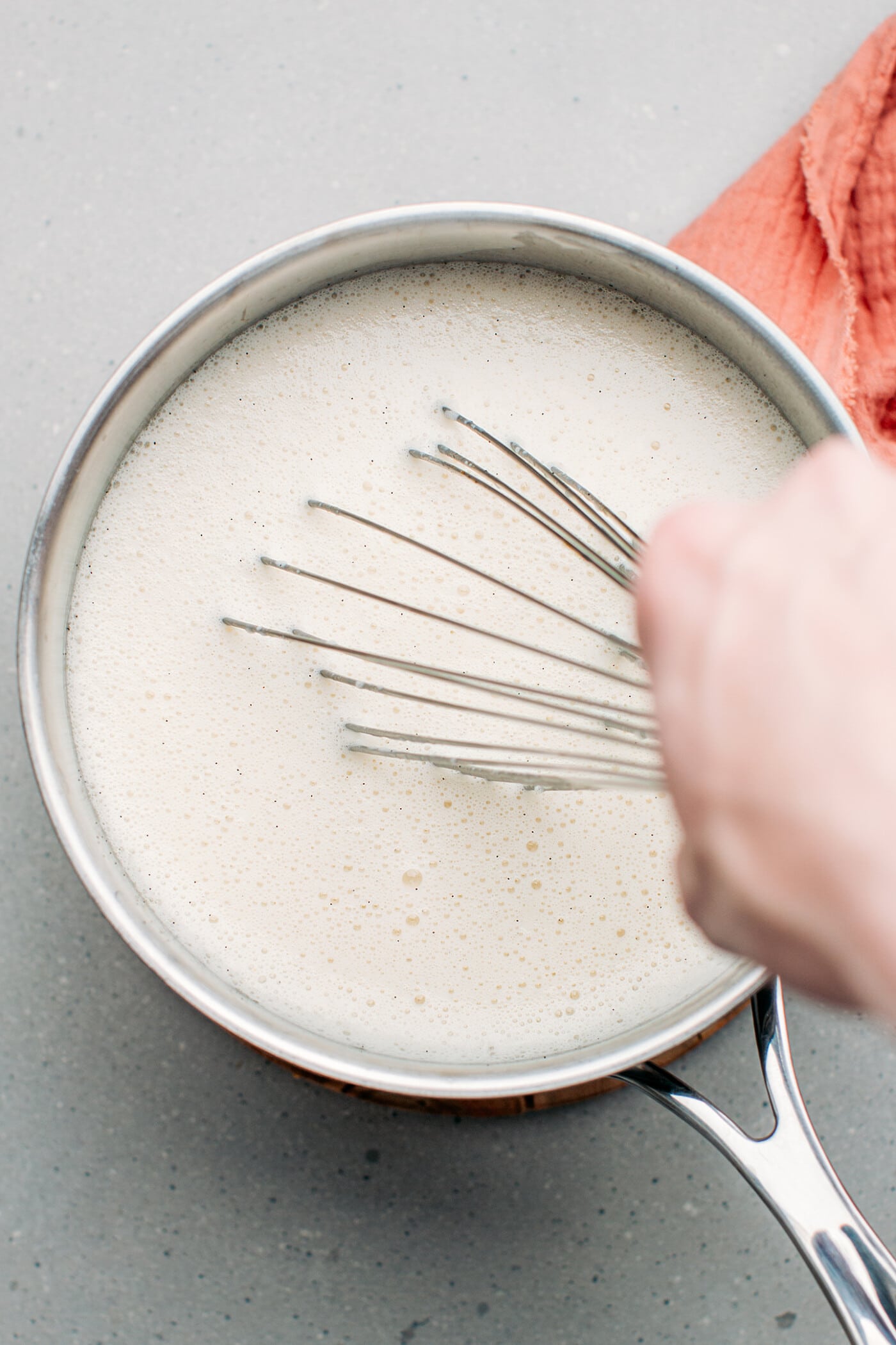 Whisking vanilla ice cream in a saucepan.