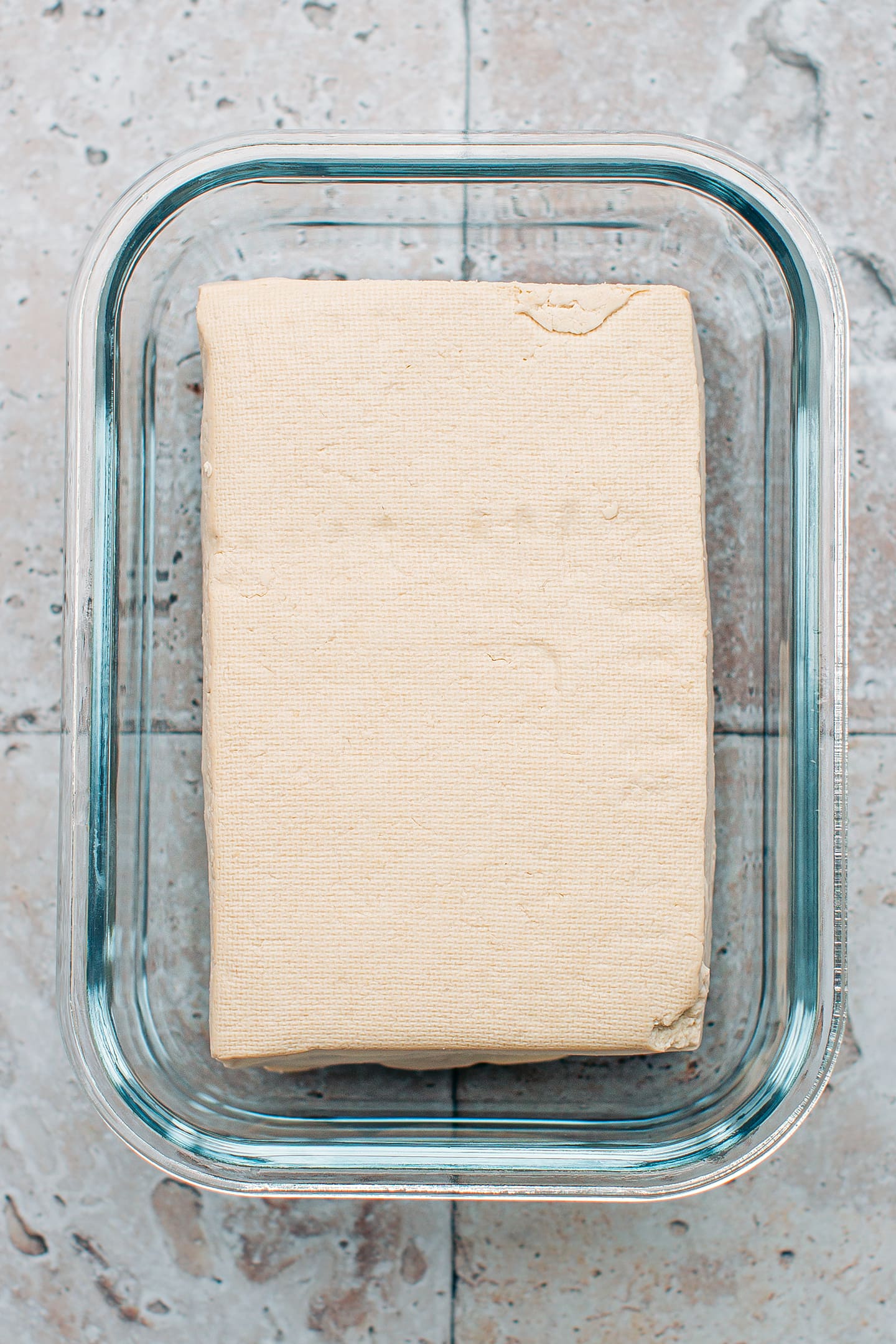 Firm tofu in a glass dish.