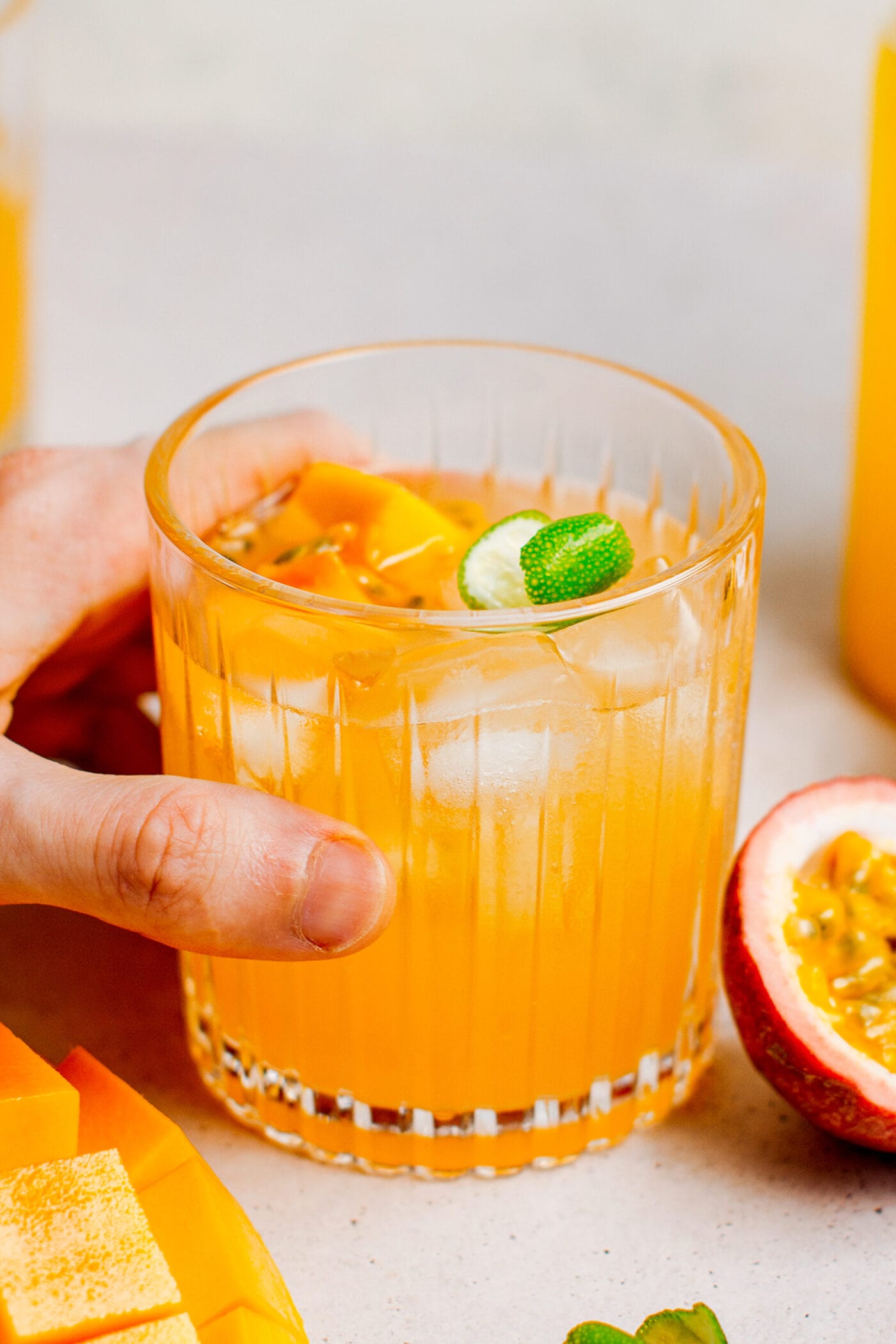 Holding a glass of mango liquor with mango chunks and passion fruit.