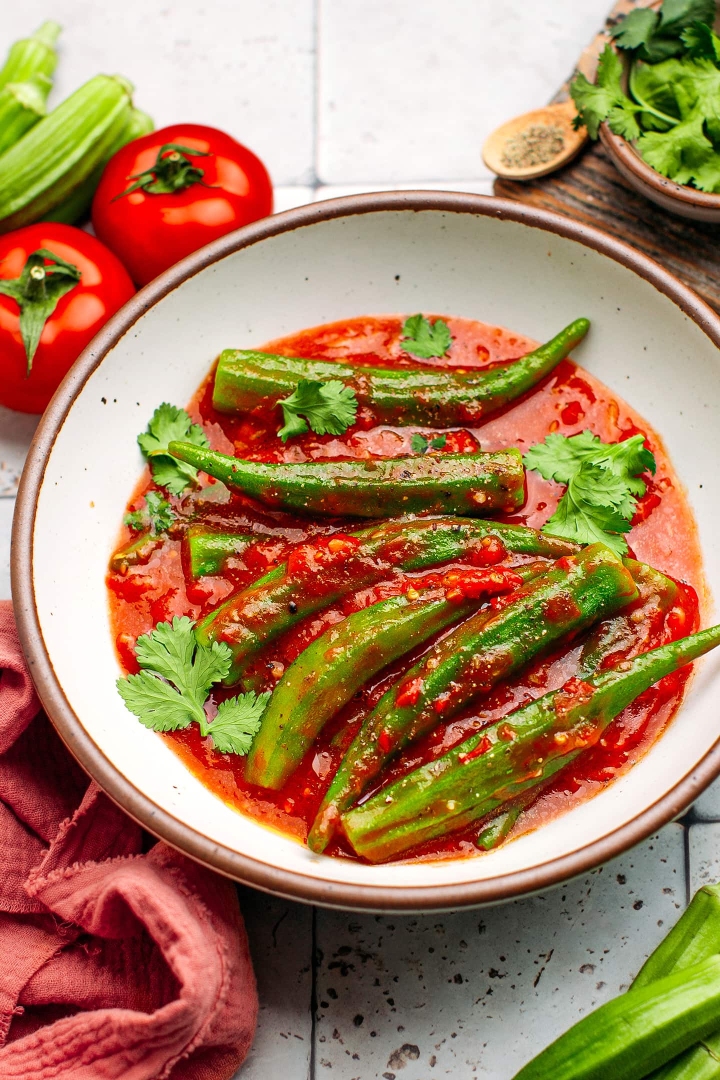 Okra pods and tomato sauce topped with cilantro in a bowl.