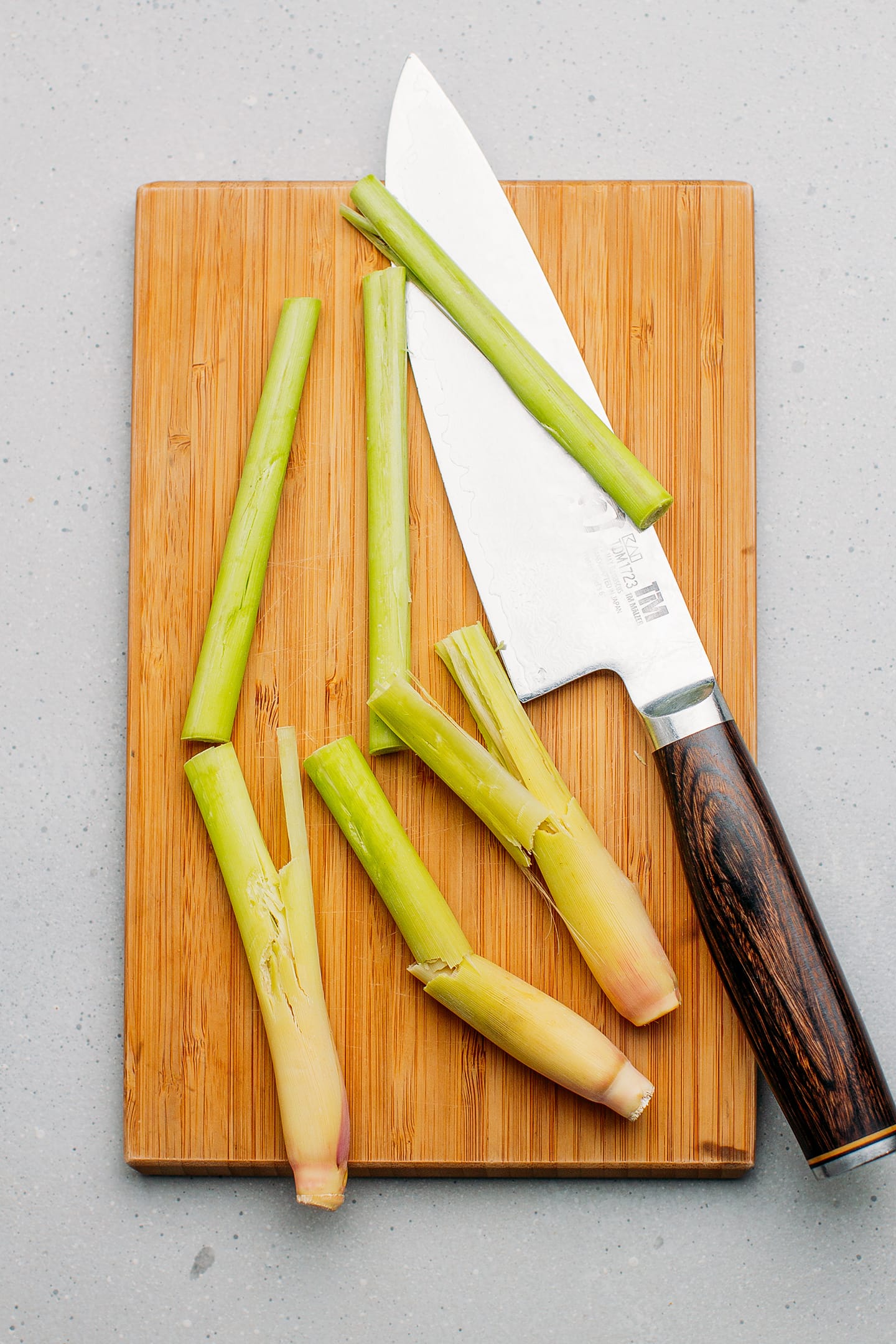 Sliced and crushed lemongrass stalks on a cutting board.