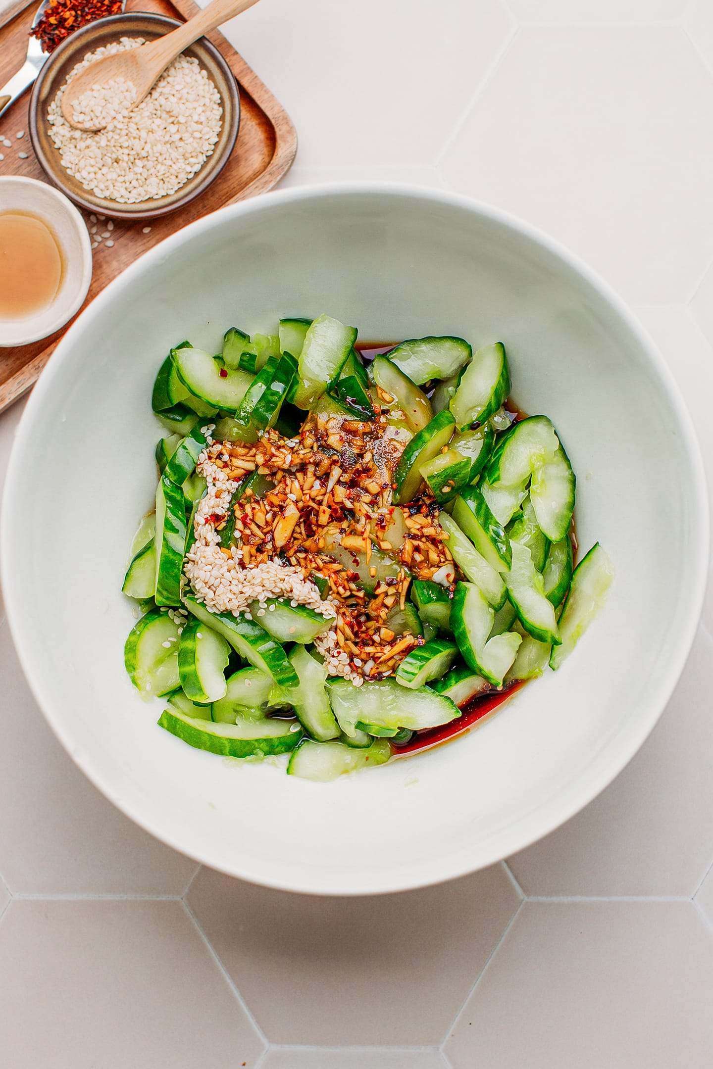 Smashed cucumbers, sesame seeds, soy sauce, and vinegar in a bowl.