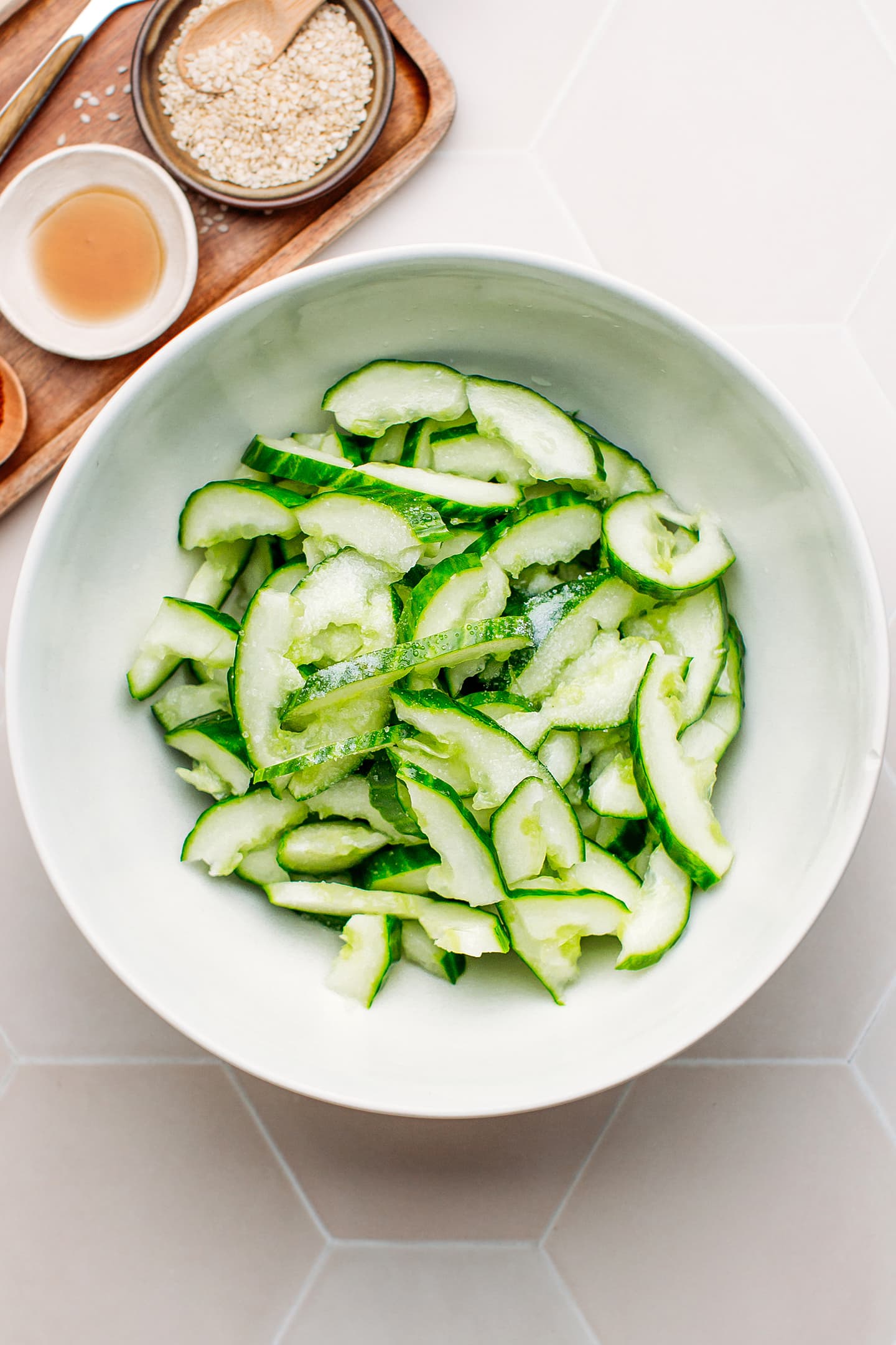 Smashed cucumbers and salt in a mixing bowl.