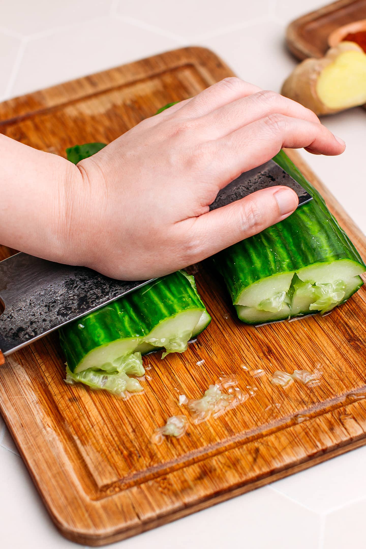 Smashing cucumbers using a large knife.