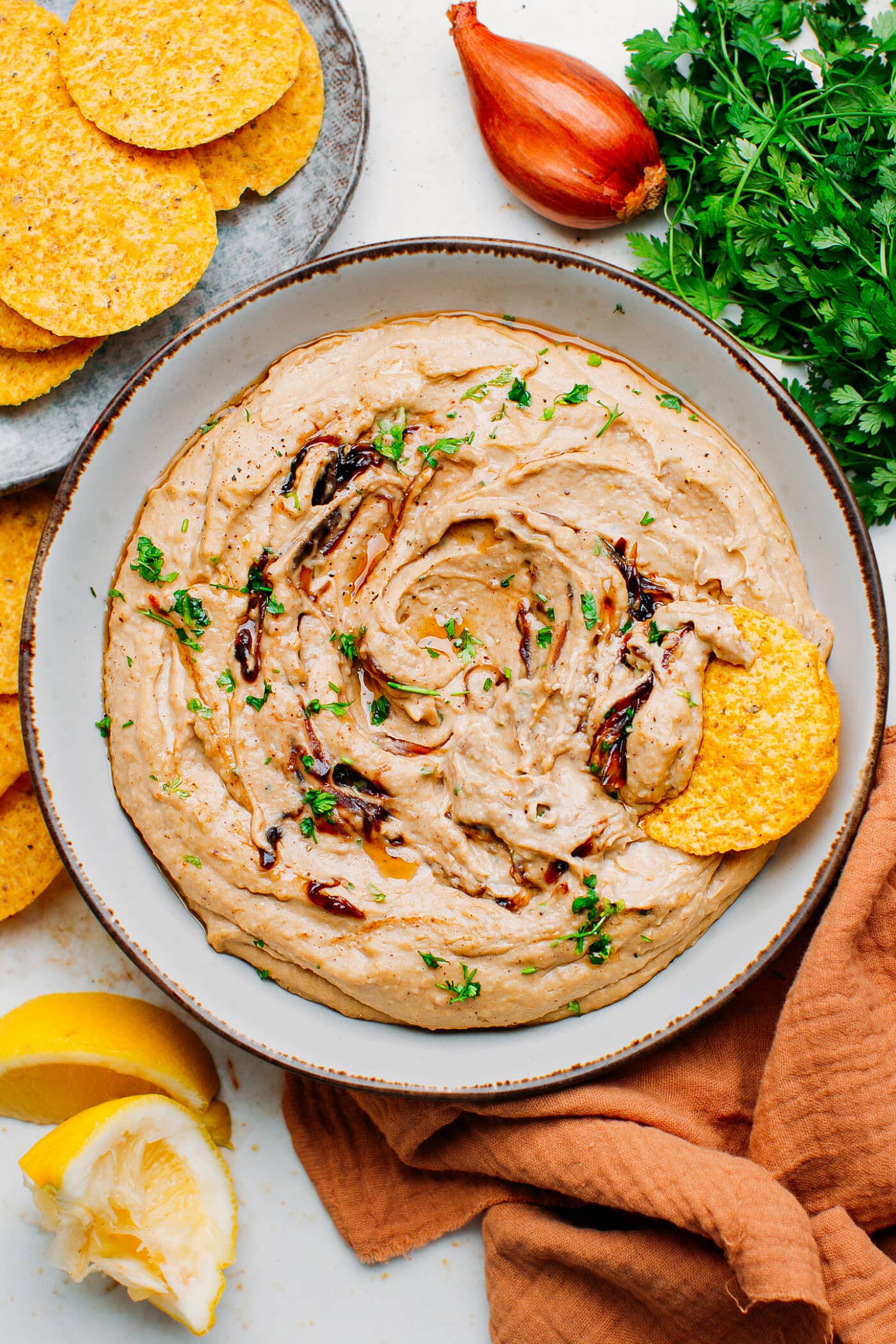 Caramelized shallots hummus in a plate with tortilla chips.