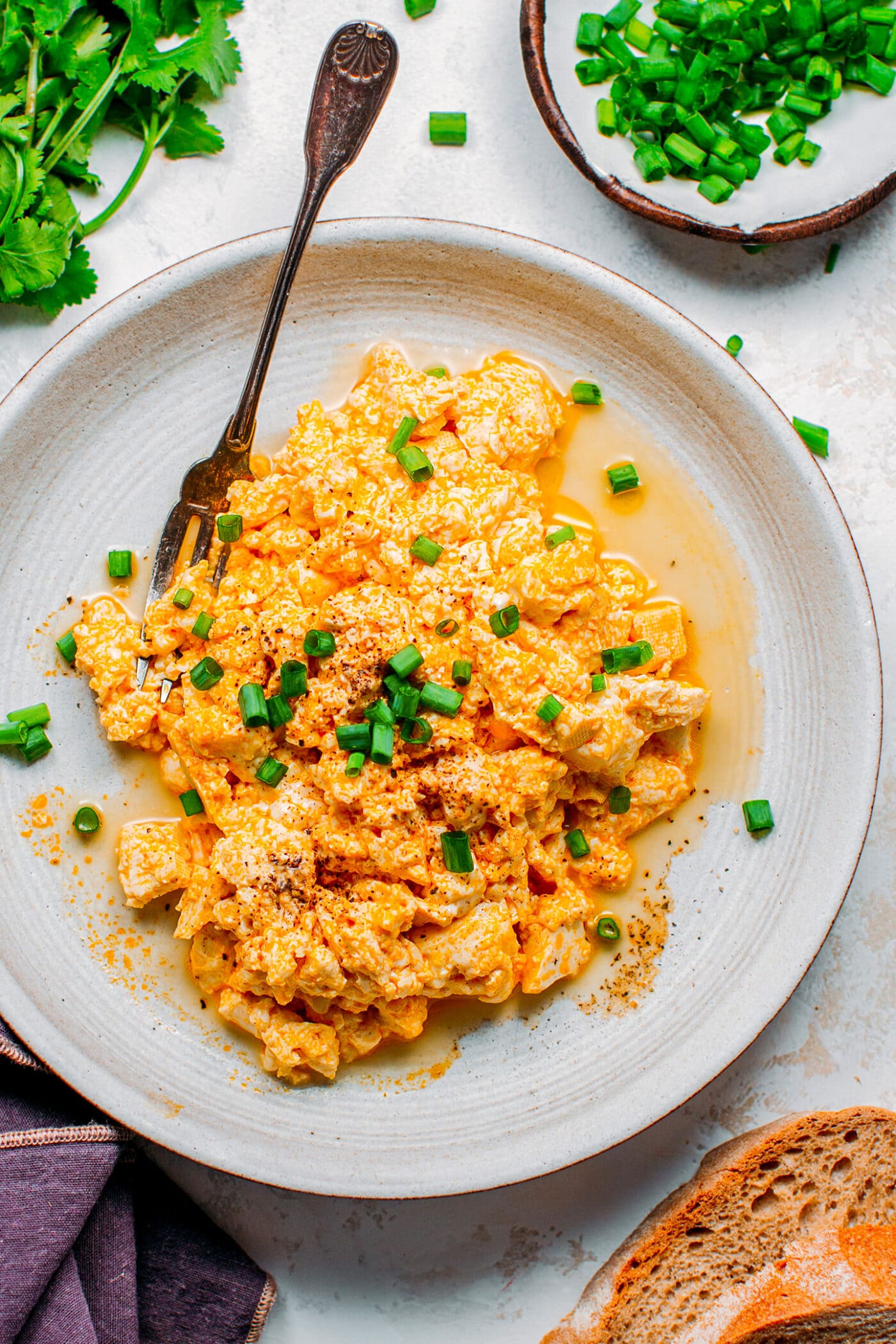 Tofu scramble on a plate with scallions and black pepper.