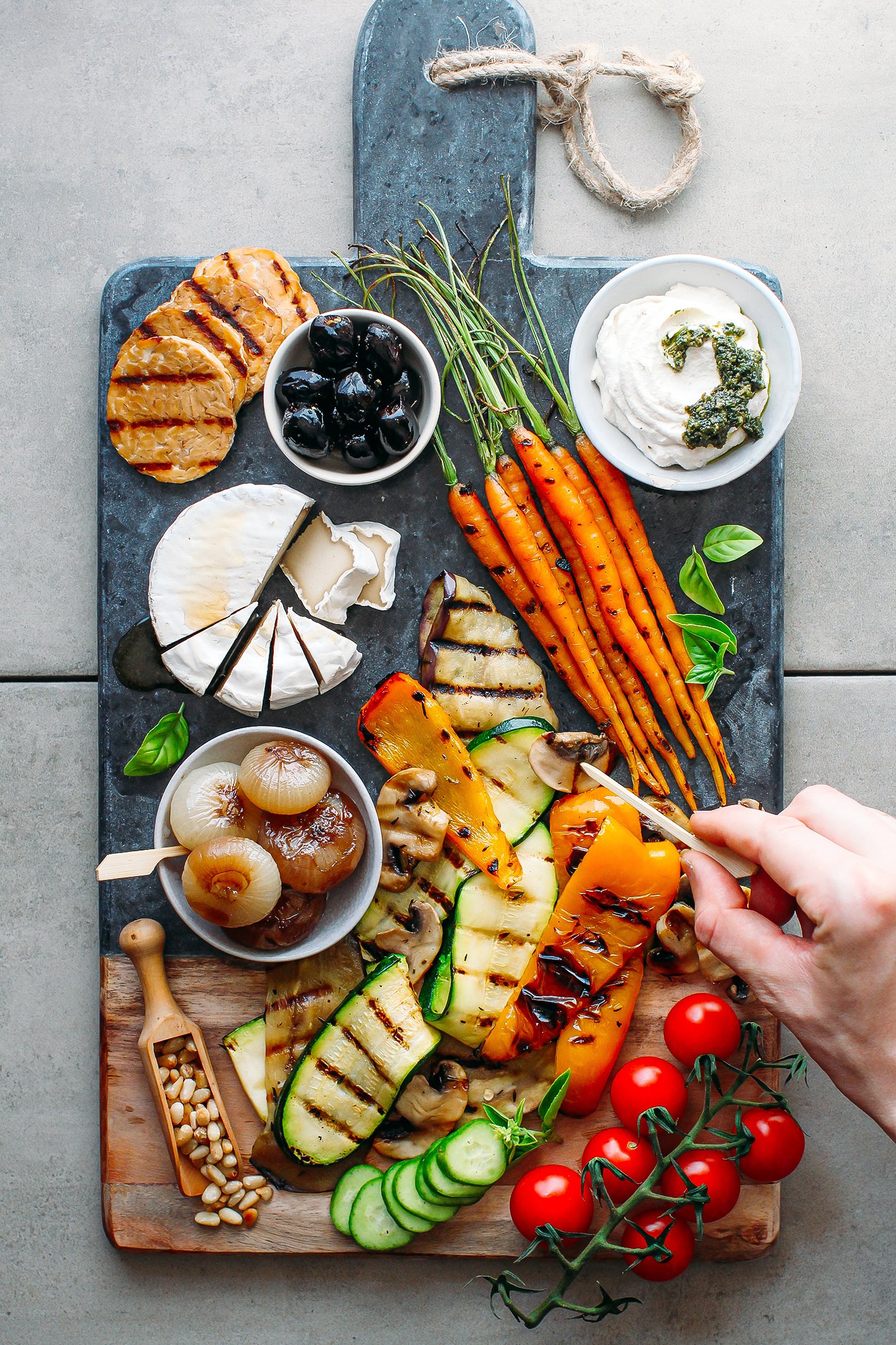 Loaded vegan antipasto platter with grilled veggies, cheeses, and nuts.