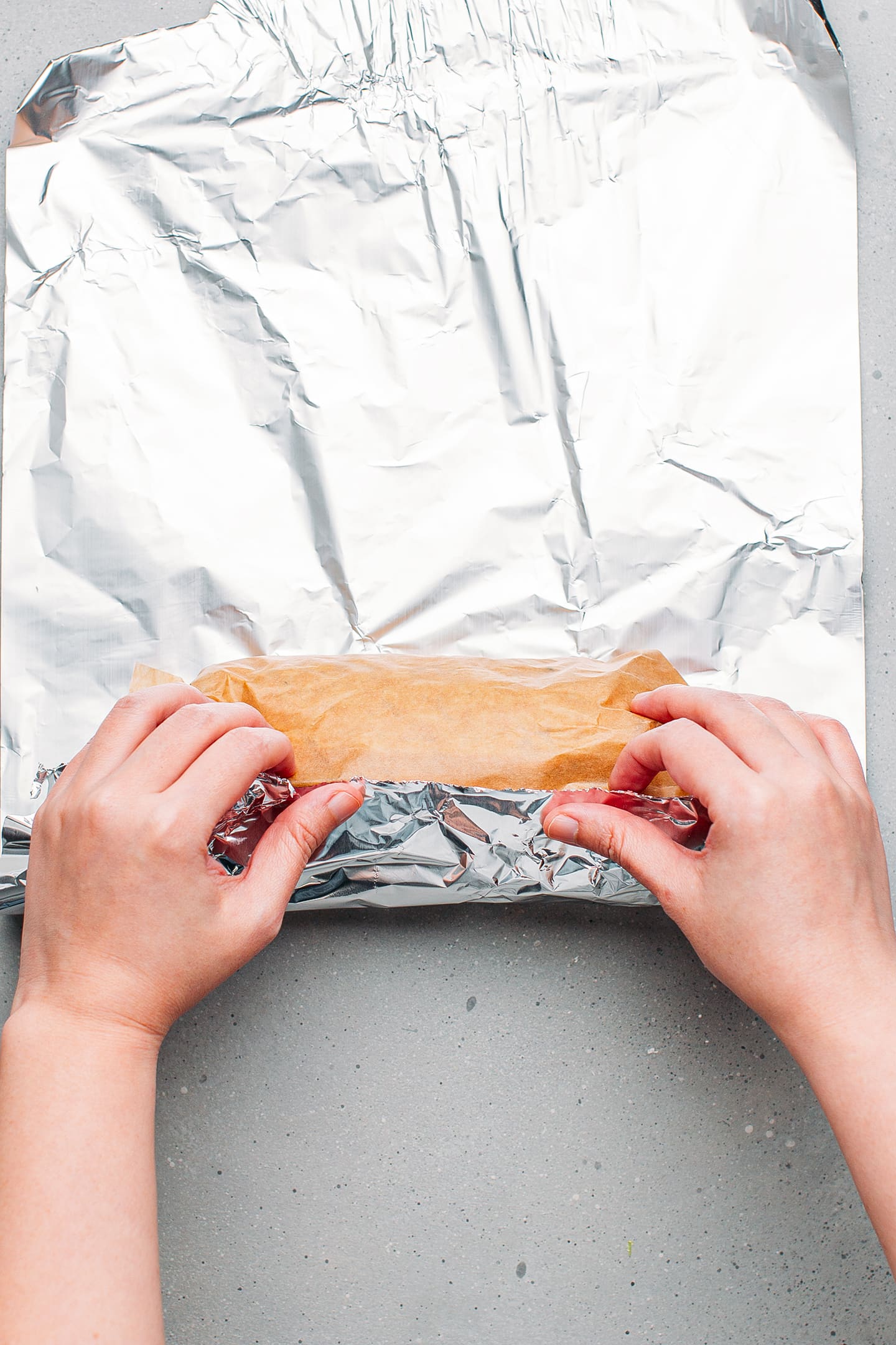 Rolling vegetarian bologna in a piece of aluminum foil.