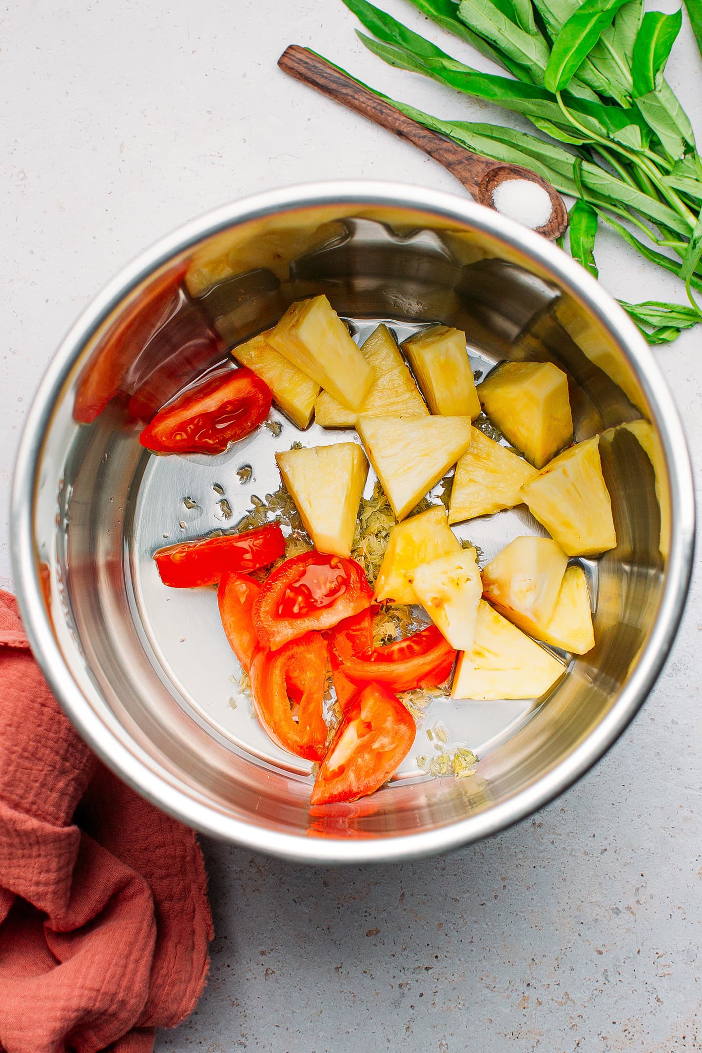 Diced pineapple and tomatoes in a pot.
