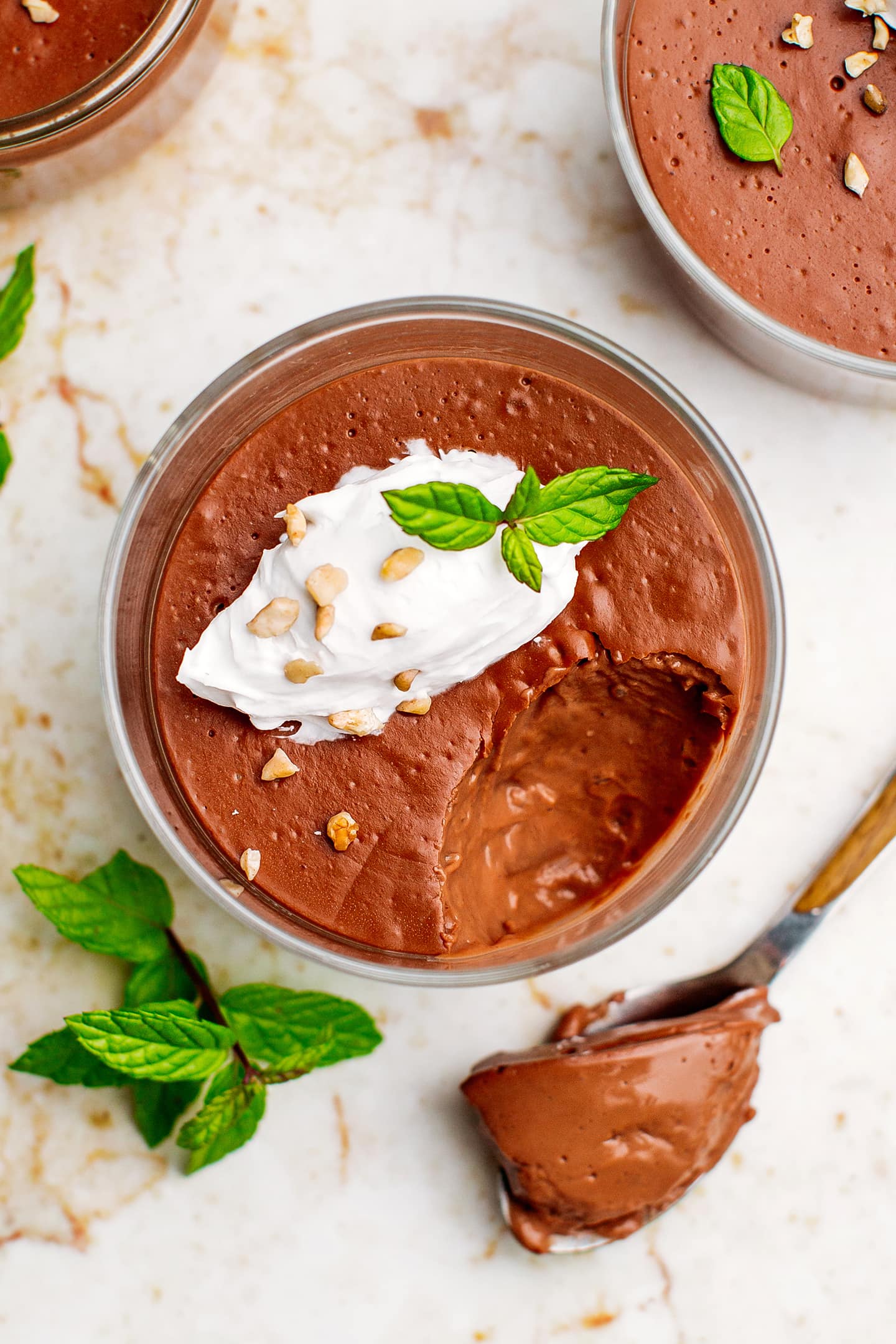 Top view of chocolate pots de crème with coconut cream and crushed nuts.