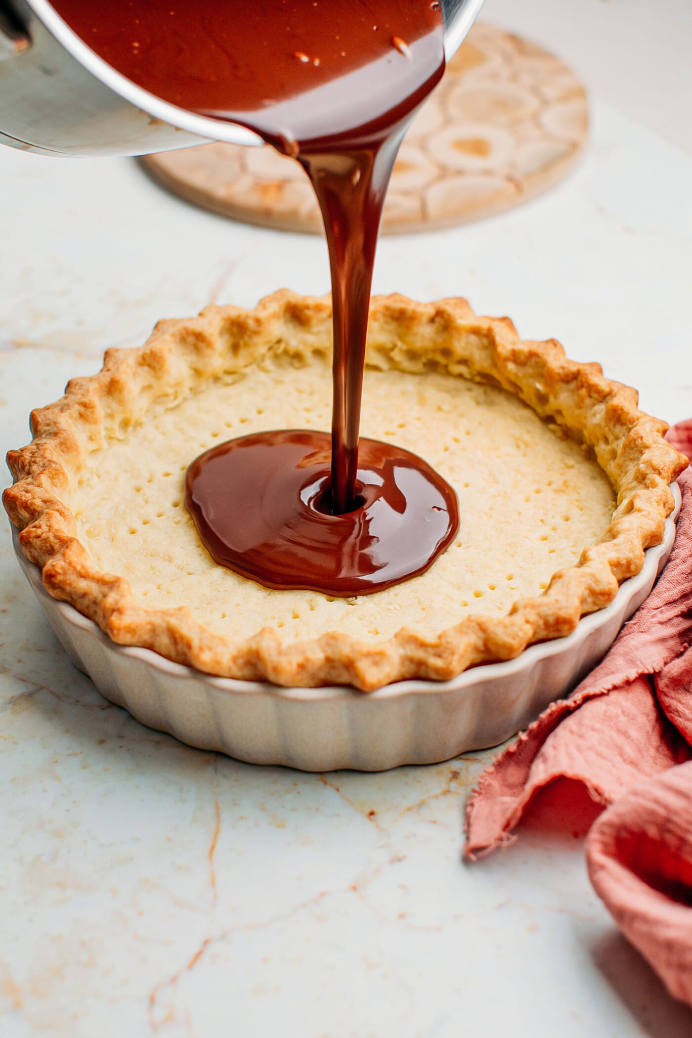 Pouring chocolate ganache into a baked pie crust.