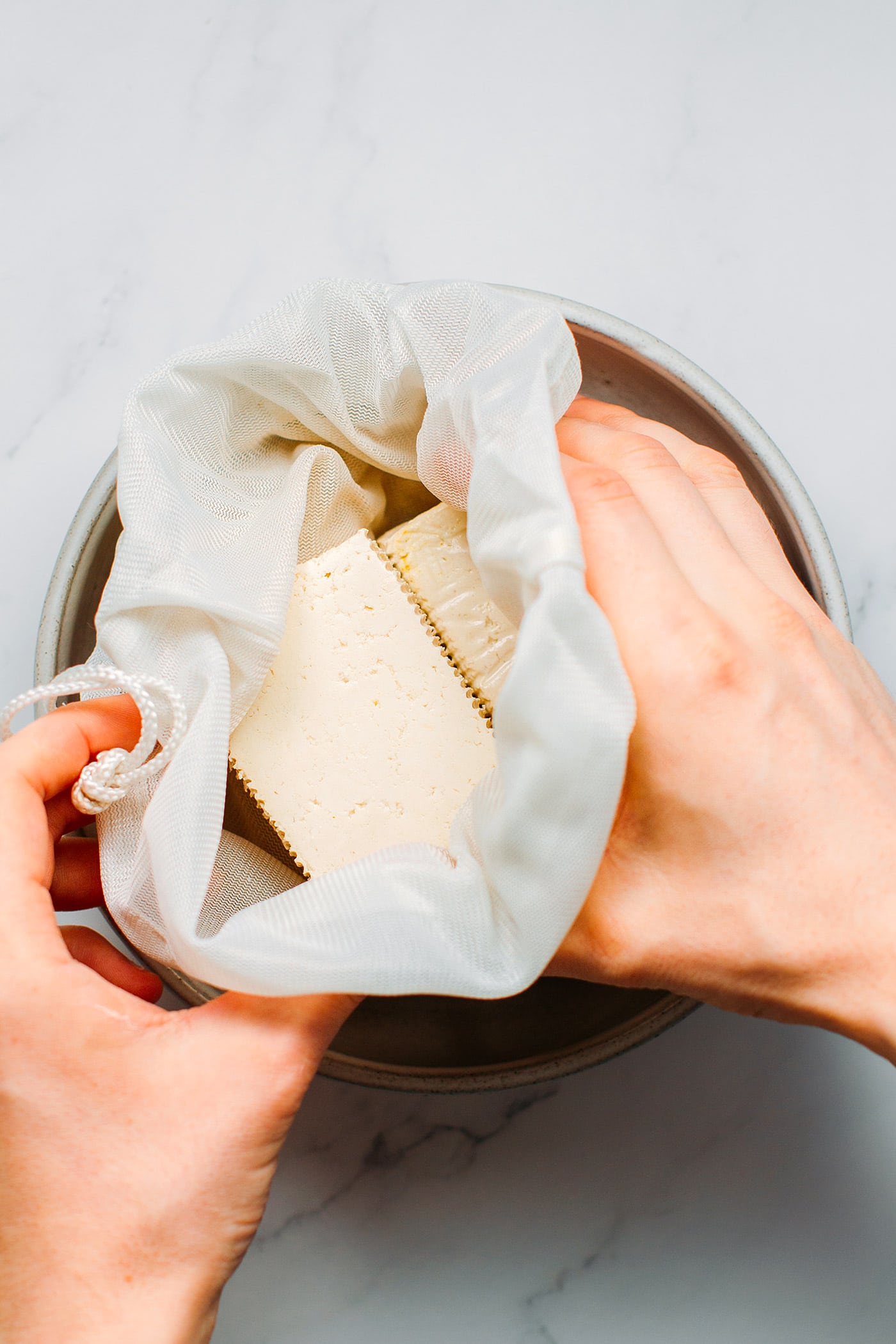 Squeezing tofu to prepare vegan sausages