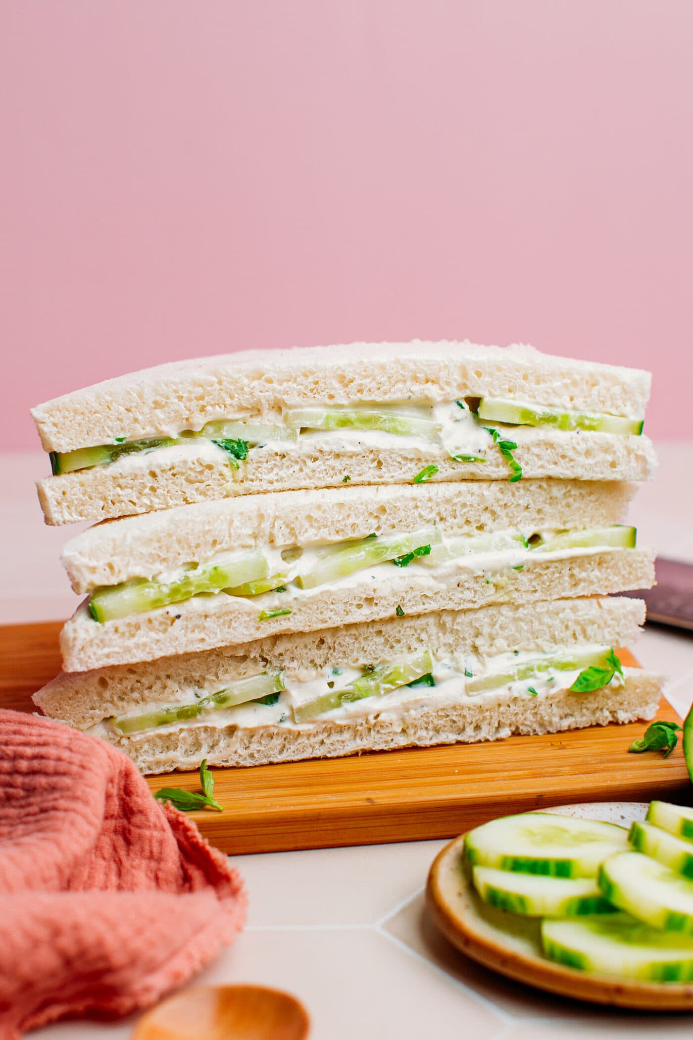 Cucumber sandwiches on a chopping board.