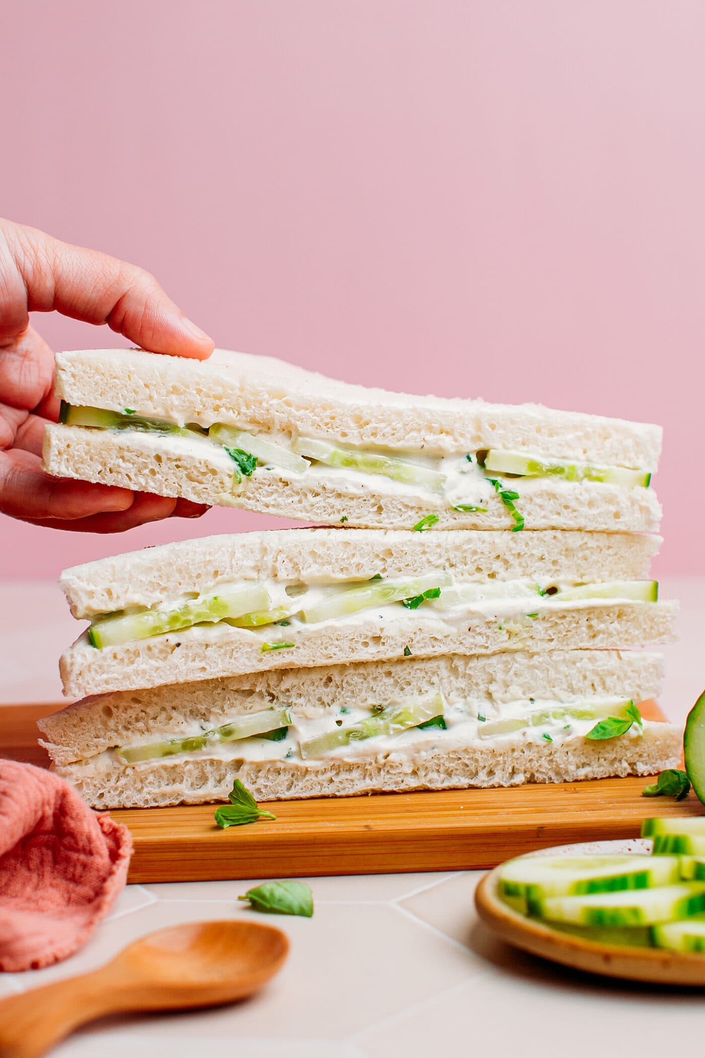 Hand holding a slice of cucumber sandwich.