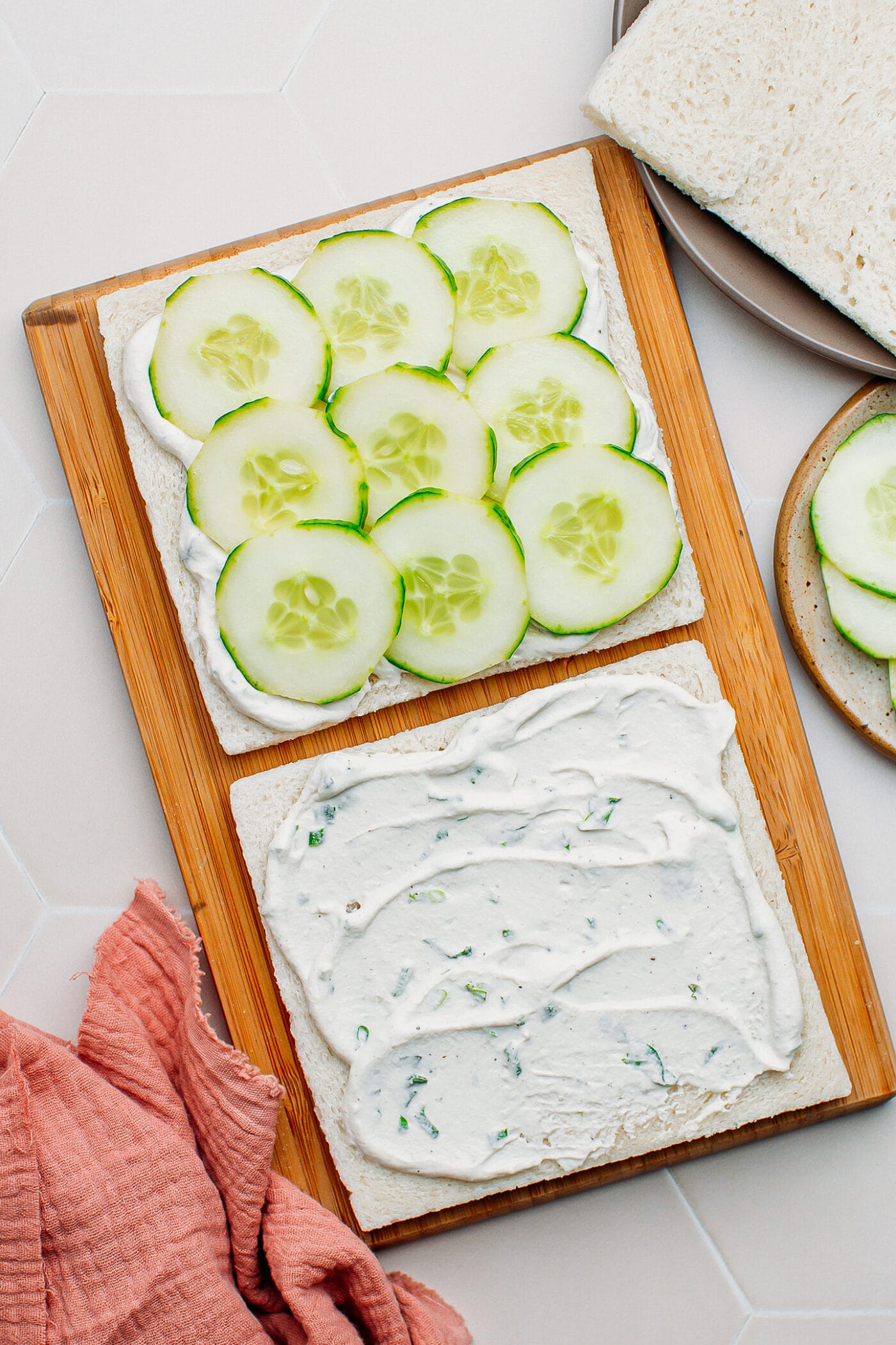 Sandwich slices topped with cucumber slices and vegan cream cheese.