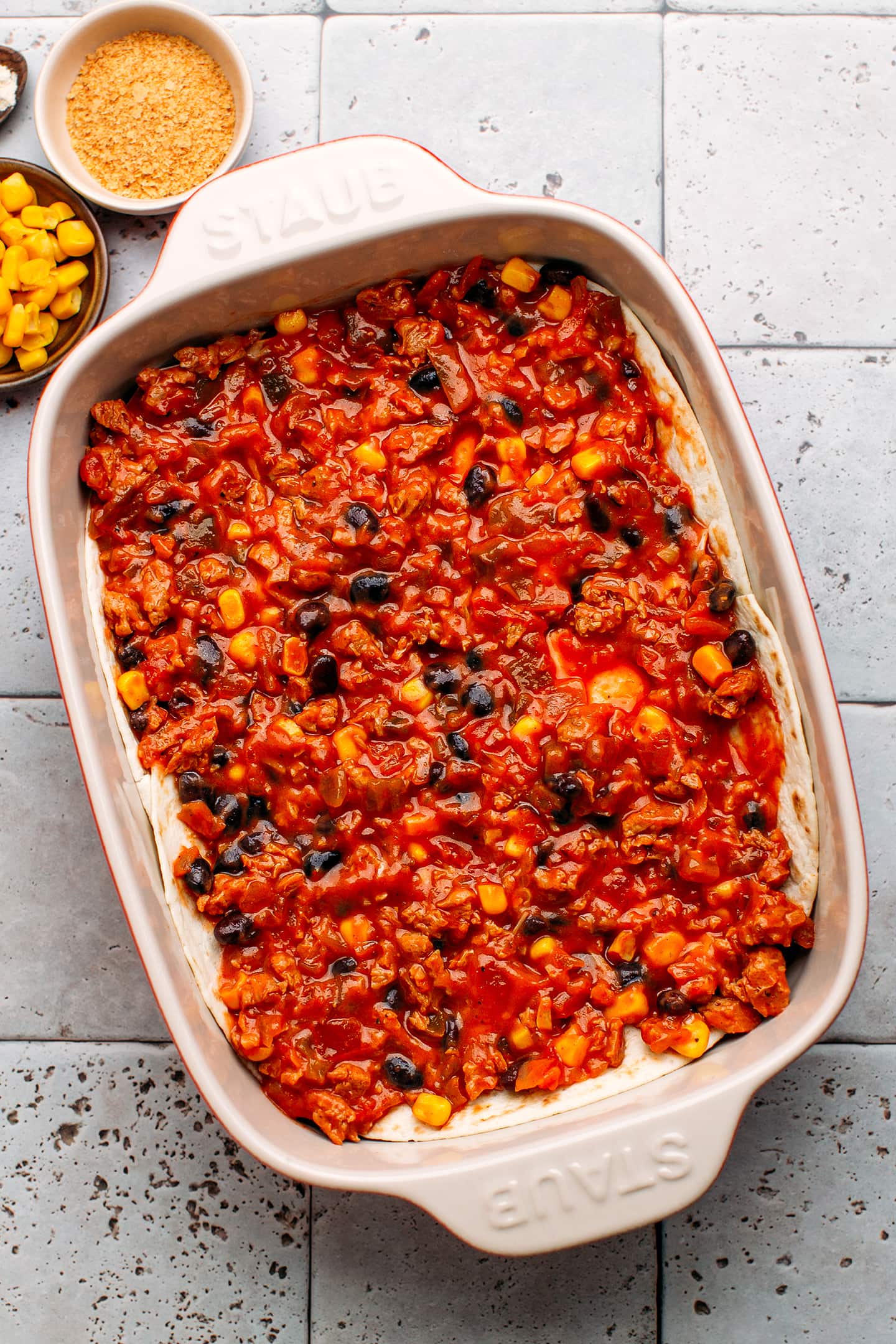 Enchilada filling on top of tortillas in a baking dish.