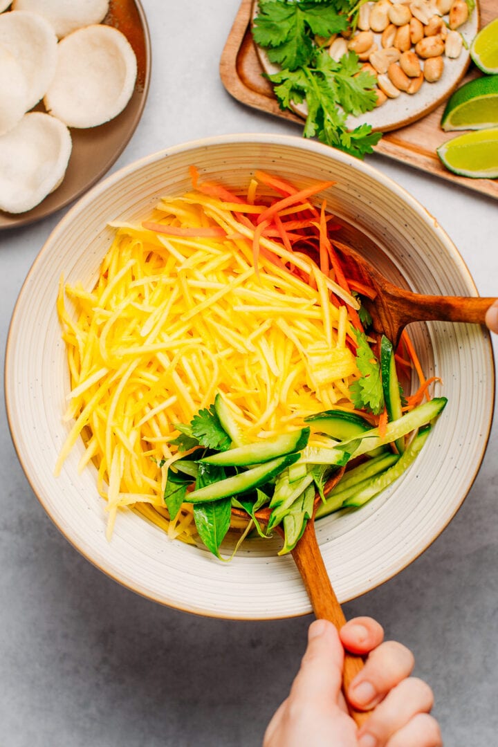 Shredded green mango, carrots, and cucumber in a bowl.