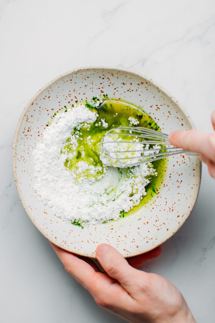 Powdered sugar, melted cacao butter, and matcha in a bowl.