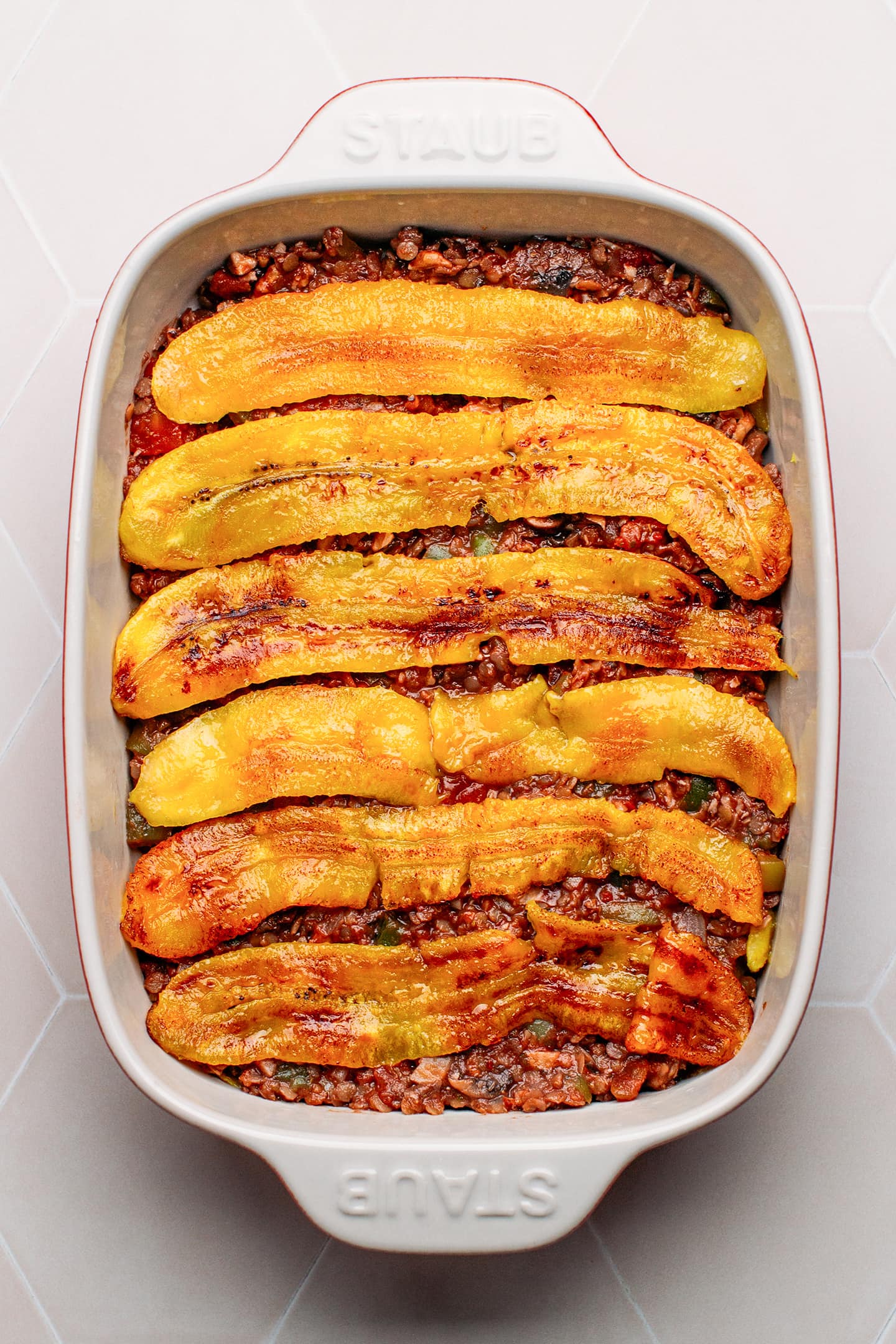 Plantains on top of vegan bolognese in a baking dish.