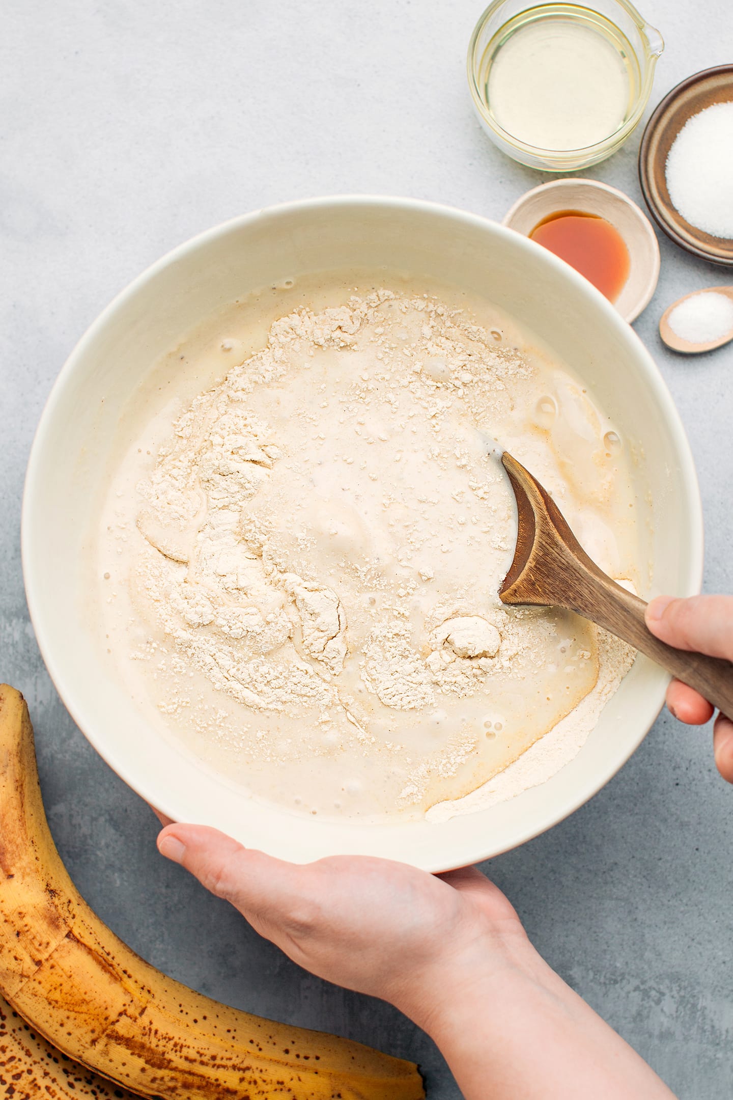 Mixing banana bread batter in a mixing bowl.