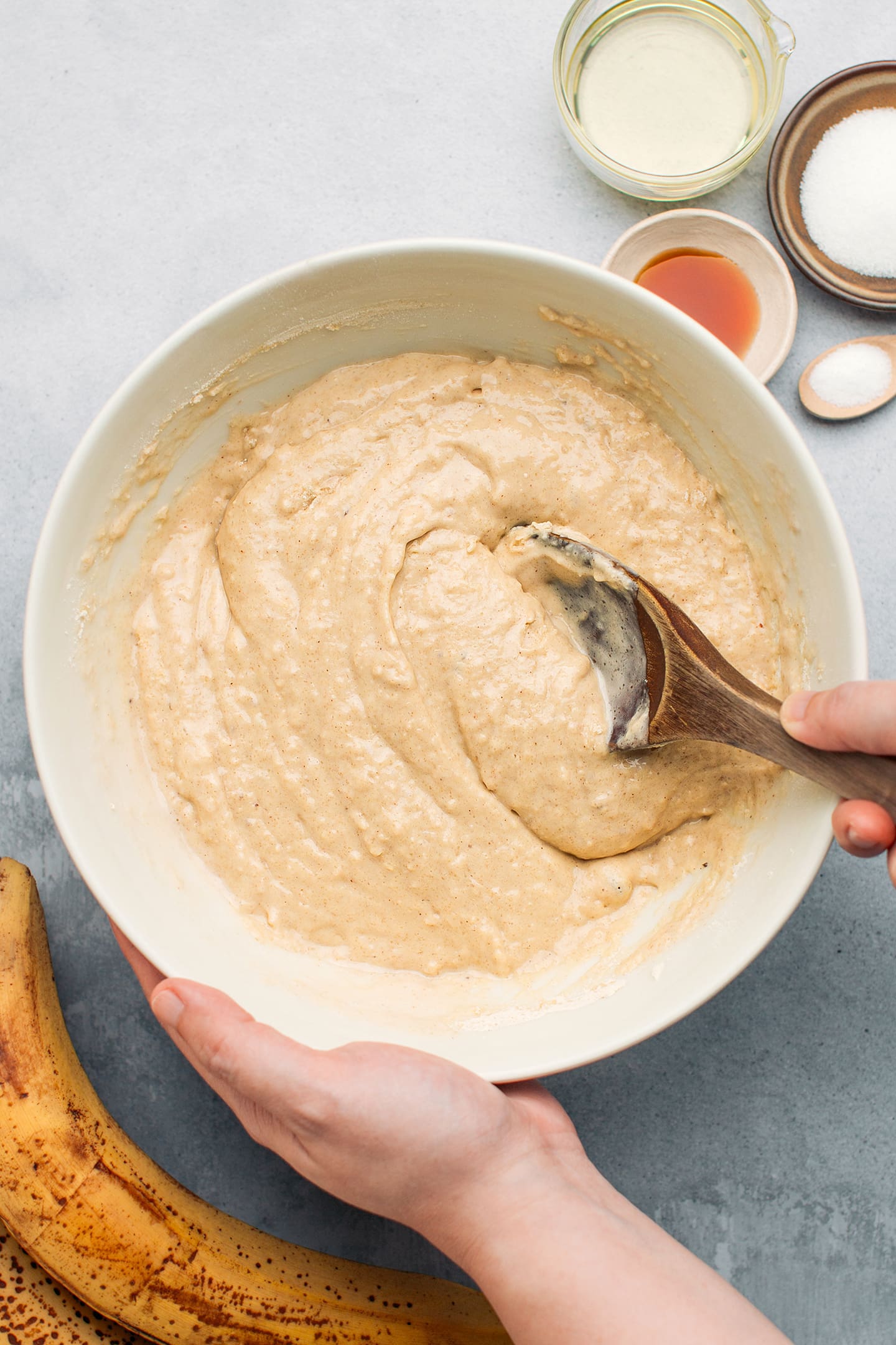 Mixing banana bread batter in a mixing bowl.