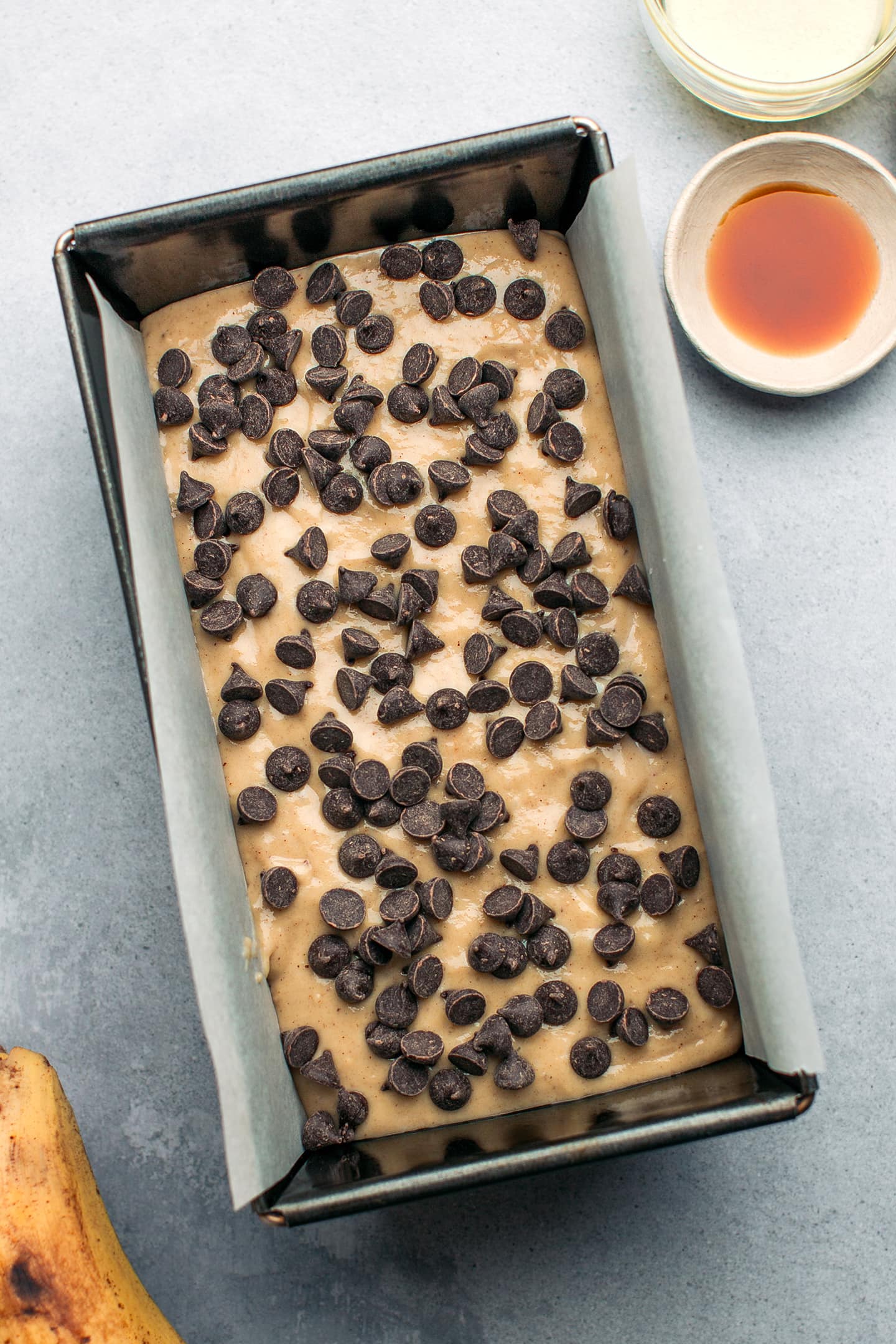 Banana bread batter topped with chocolate chips in a loaf pan.