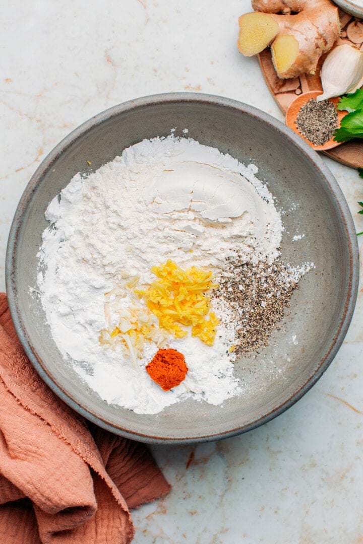 Flour, garlic, ginger, and red curry paste in a bowl.