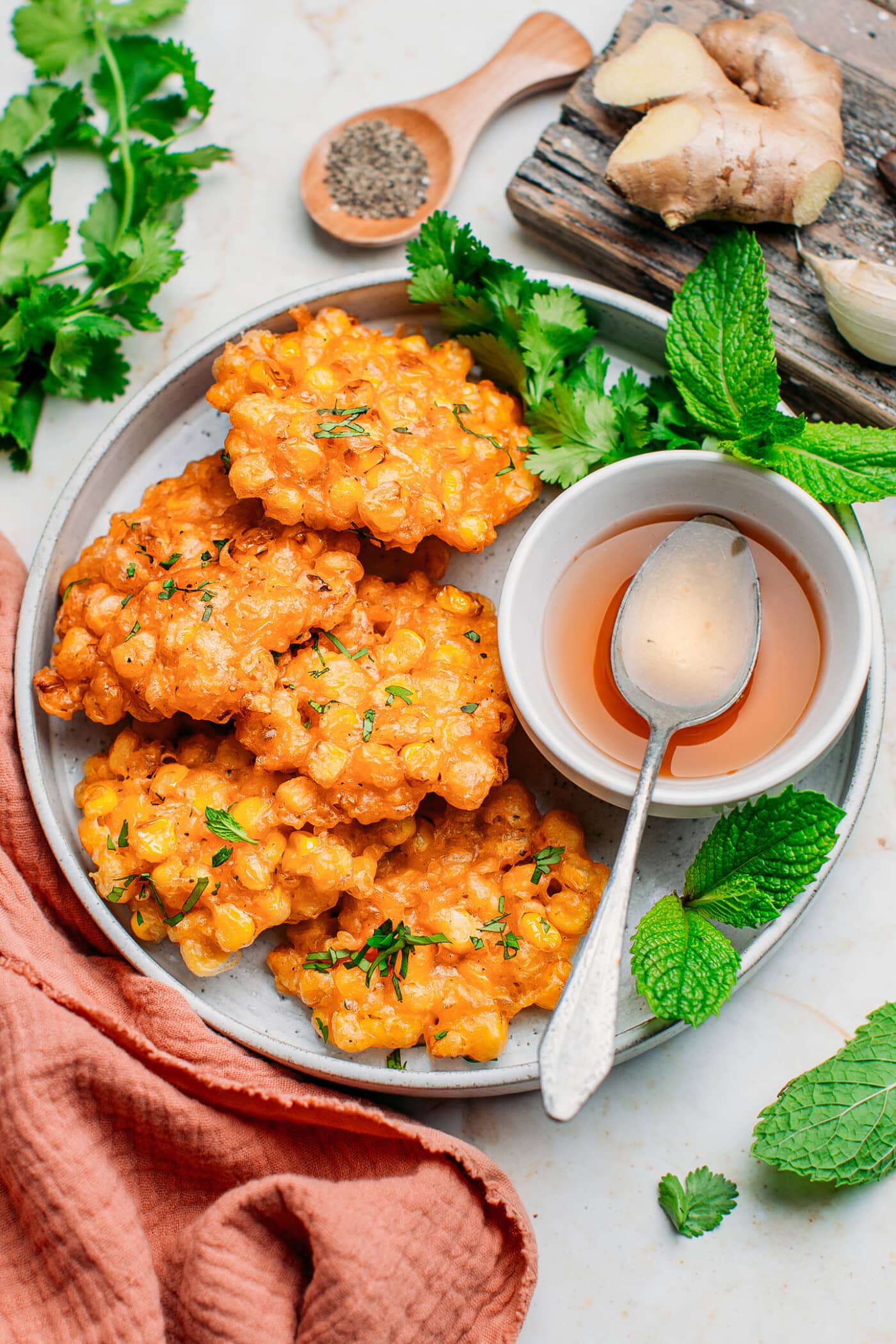 Corn fritters topped with cilantro and mint on a plate.