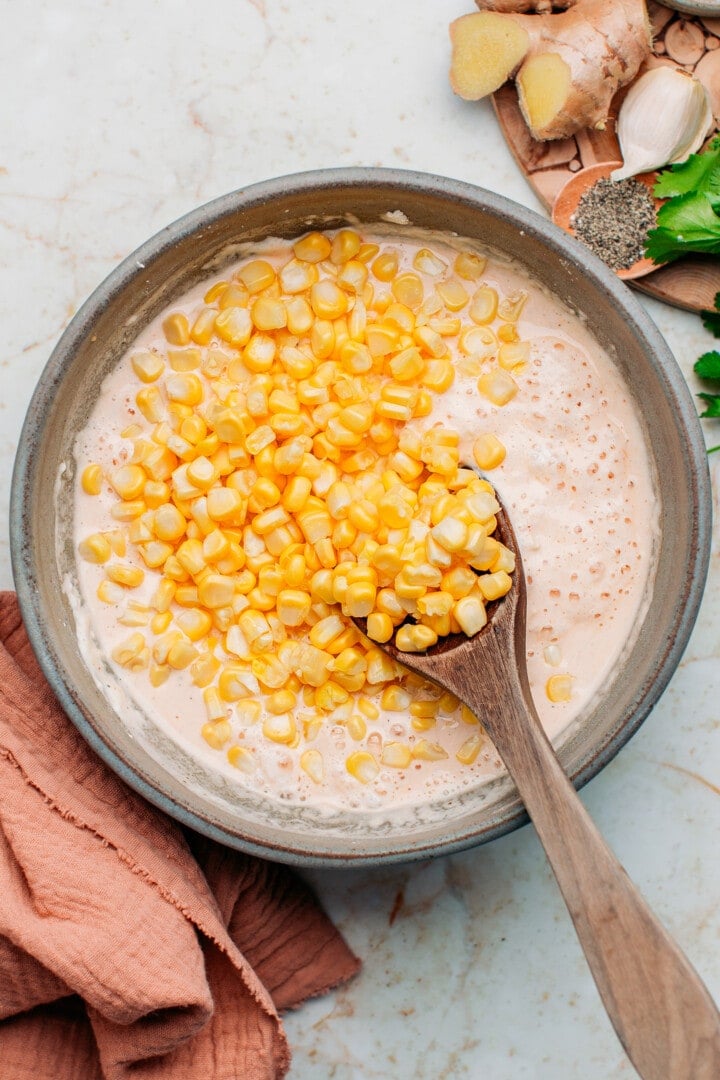 Corn kernels added to a flour batter, in a bowl.
