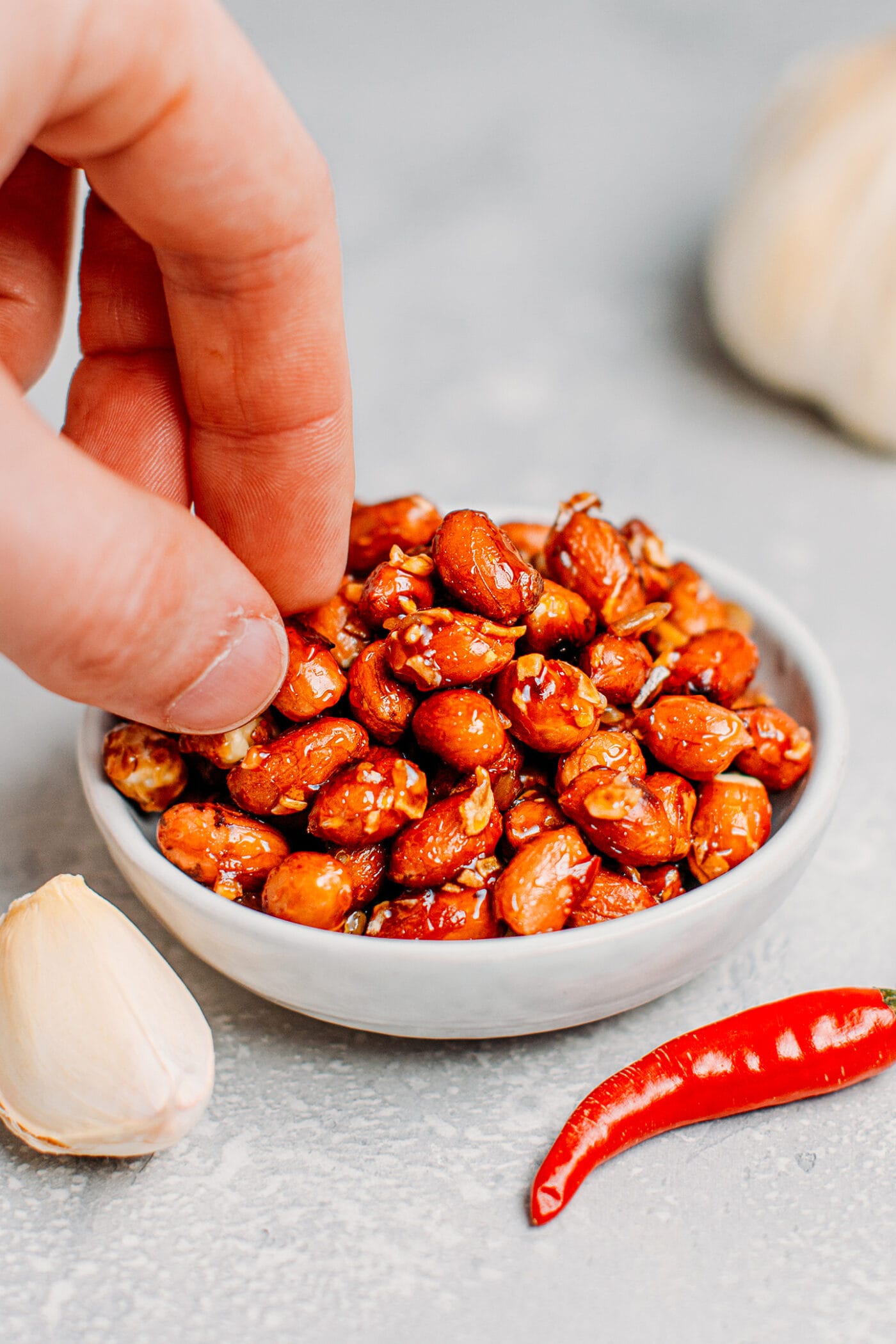 Picking chili and garlic peanuts from a bowl.