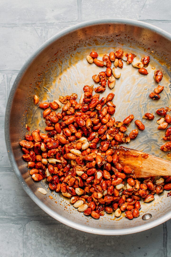 Stirring peanuts with caramel, chili, and garlic.