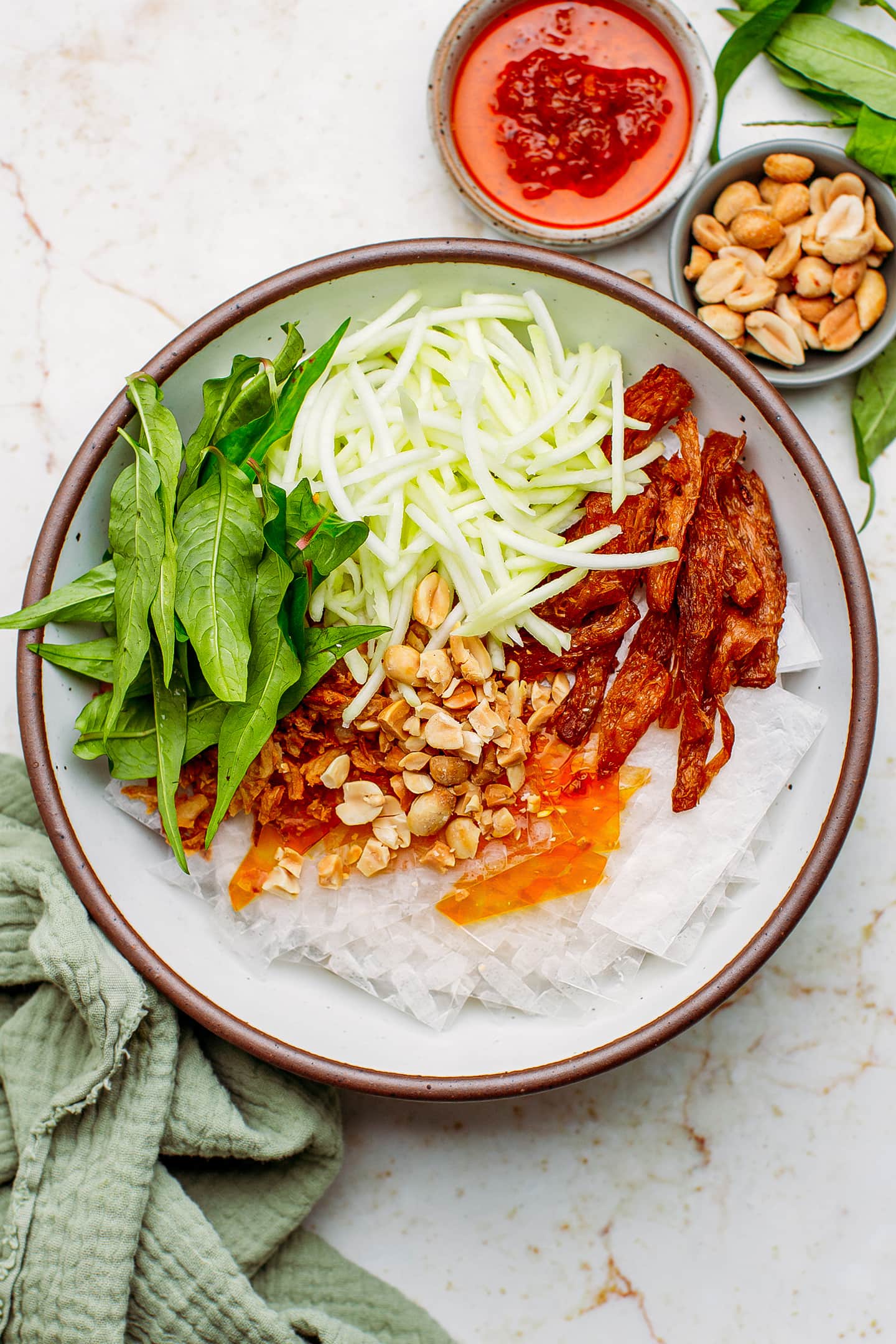 Shredded green mango, rice paper, peanuts, and Vietnamese coriander in a bowl.